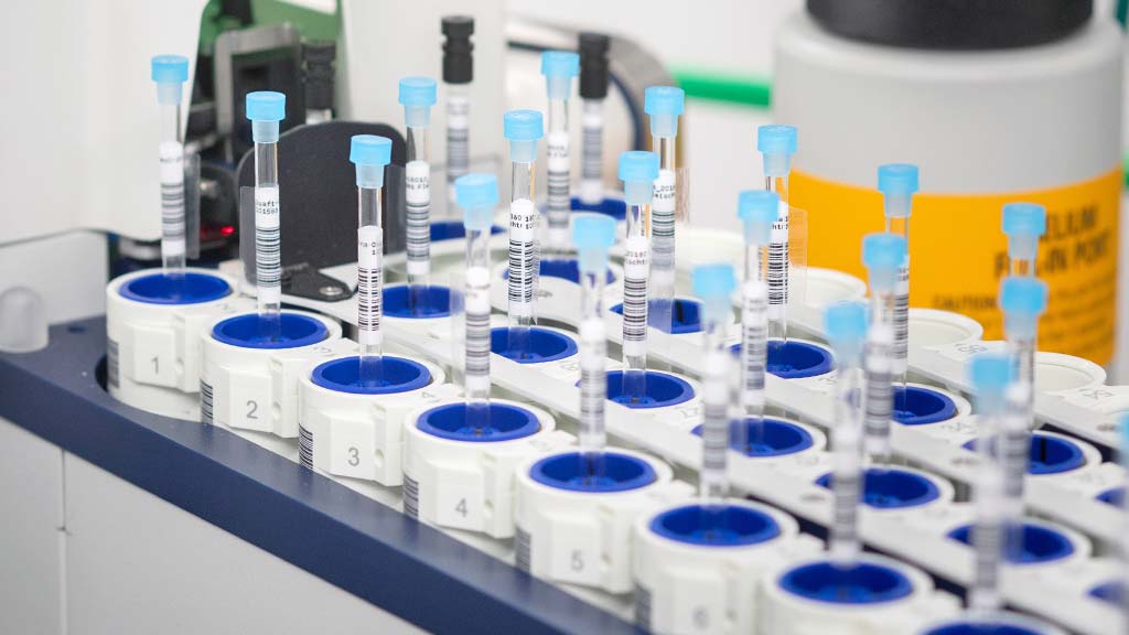 Reihe nummerierter Probenröhrchen mit blauen Verschlüssen in einem Laborautomaten für chemische Analytik; automatische Probenvorbereitung und Qualitätskontrolle im modernen Analyselabor